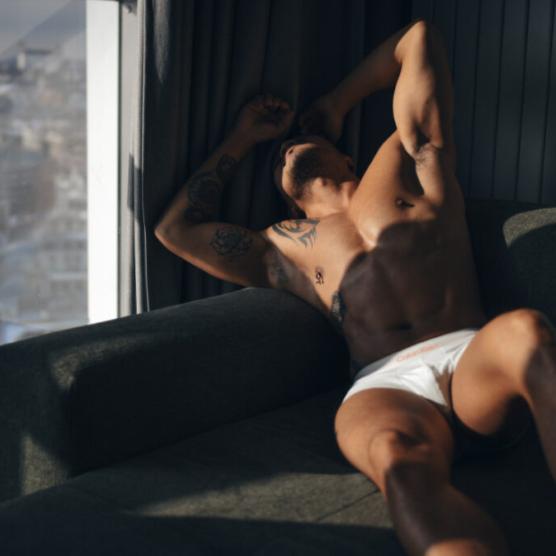 A man stretches on a sofa with the Bratislava Castle visible through the window. Premium Membership View.